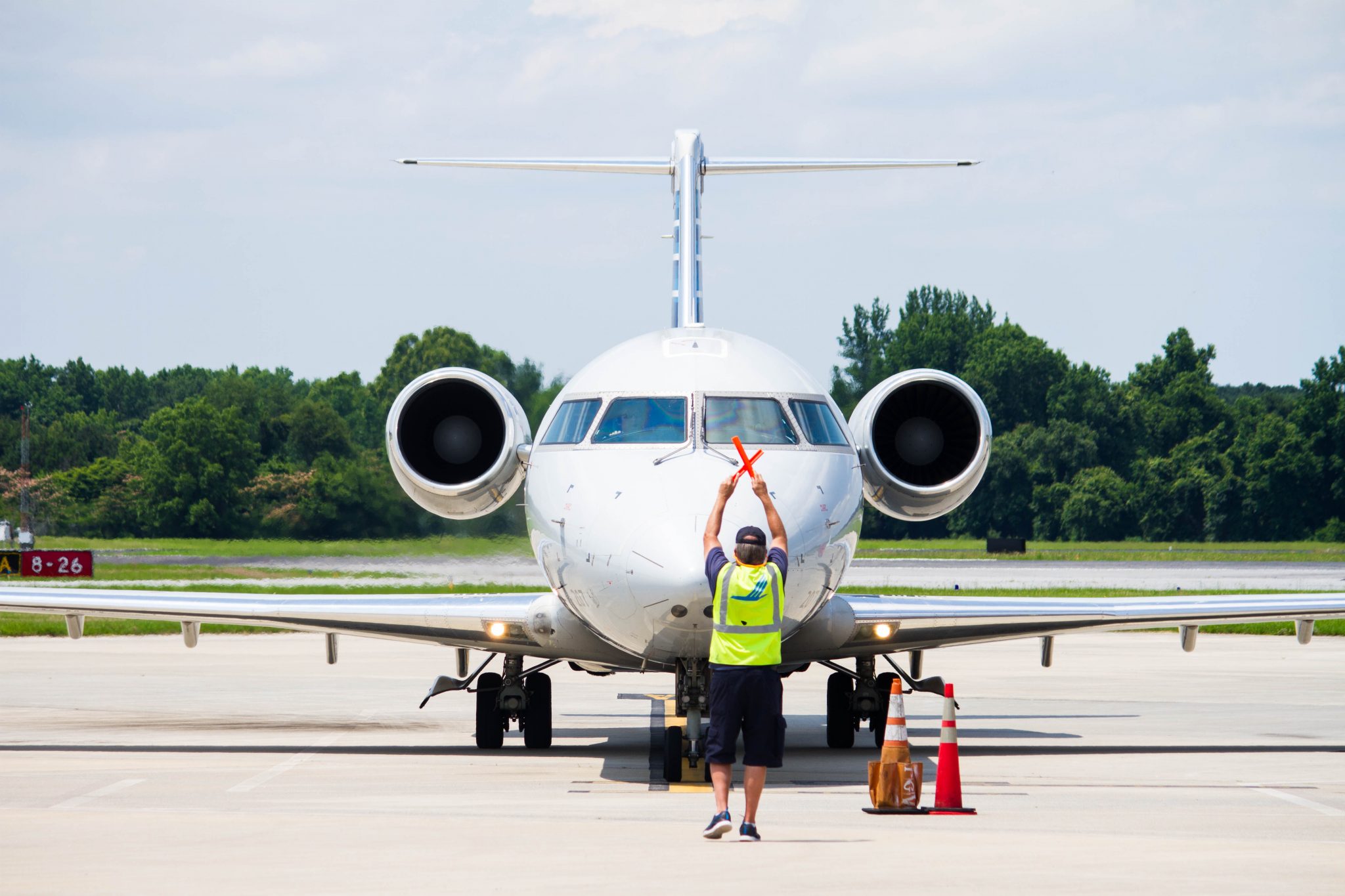 Plane on runway with marshaller